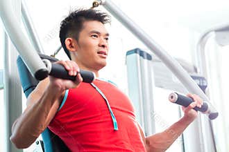 Chinese Man training strength in fitness gym