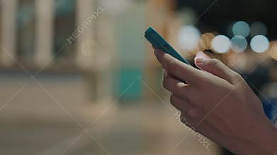 Close View. Woman Hands Holding the Green Smartphone and Texting in Internet Standing Outside at Night Street