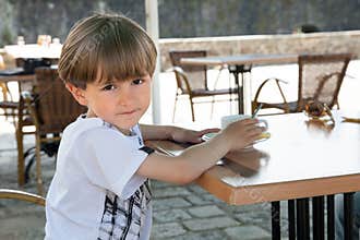The small boy sits in cafe