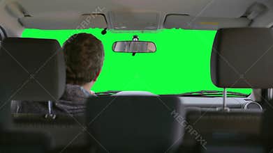 Man drives a car against a green background