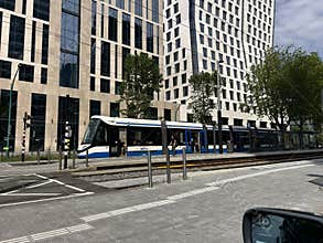 Modern tram stop beside glass office towers in dense urban district with