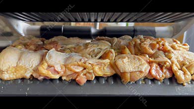 Electric contact grill closing on raw marinated chicken meat before cooking at home