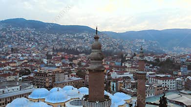 Aerial drone circles Bursa Ulu Cami minaret above dense Ottoman cityscape in Turkiye, mosque, ulu camii, islamic landmark, camii
