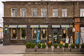 Historic facade with awnings, shrubs, and closed umbrellas on street