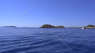 Rocky islands near Kas Antalya rise from calm Mediterranean water with small boats nearby, coast, sea, small islet, turkiye