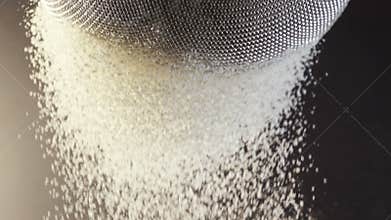 Flour falling through a metal sieve