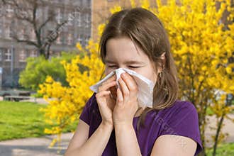 Allergy concept. Young allergic woman is sneezing and blowing her nose.