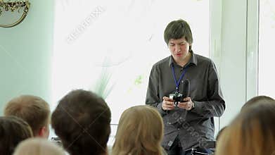 Young man speaking in class with on camera shotgun microphone in hands
