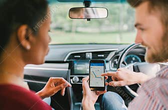 Multiethnic lover couple use navigation system on smartphone in car. Mobile phone application or crowdsourcing taxi app service