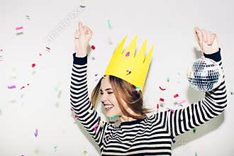 Birthday party, new year carnival. Young smiling woman on white background celebrating brightful event, wears stripped
