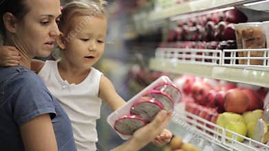 Mother with little daughter makes purchases in the supermarket