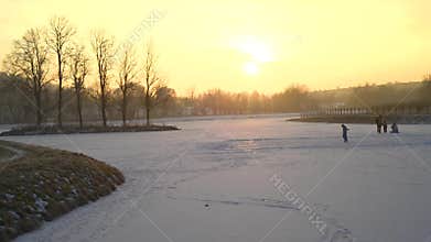 Seniors walk in a park, people ice skating on a pond lake, sunset evening