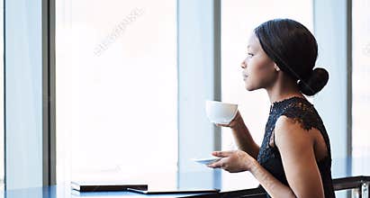 Beautiful young black woman looking thoughtfully out a large window
