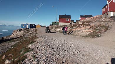 Village and people in mountains on shore of Arctic Ocean from Greenland.