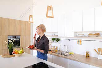 Lovely female posing and smiling at camera with plate of ripe st