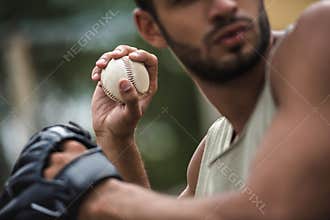 Handsome man throwing baseball ball on court