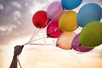 Man Hand Holding Colorful Balloons And A Beautiful Sunset. Birthday Party Balloons