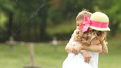 Little boy takes the girl in her arms and they so spin around in the park. Slow motion