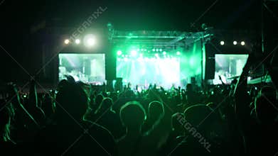 Fans jump and dance at concert, excited audience waving hands at rock festival, arms raised of crowd in bright lights