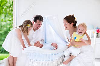Family with kids playing with newborn baby