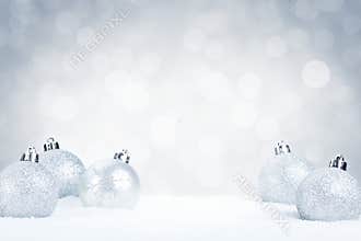 Silver Christmas baubles on snow with a silver background