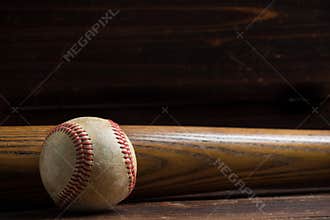 A wooden baseball bat and ball on a wooden background
