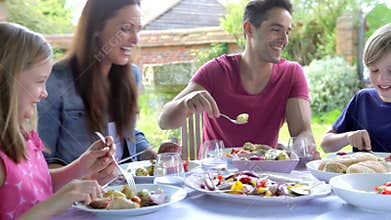 Family Sitting Outdoors Around Table Eating