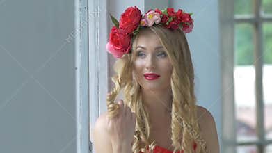 Beautiful young woman with wreath of red flowers