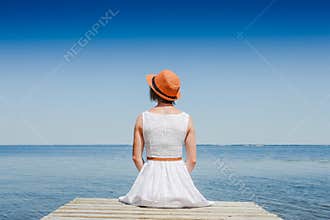 Young woman in white dress sunbathing at the seaside