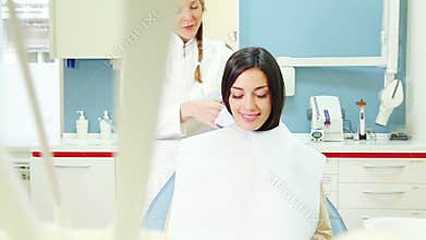 Beautiful woman sitting in dental chair while dentist preparing her for check up