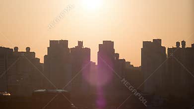 Time lapse shot of sun rising and moving in the sky, city modern buildings on the foreground. Seoul, South Korea