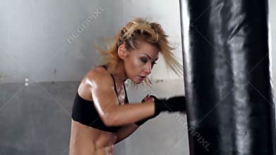 A beautiful and fit woman has a kickboxing training.