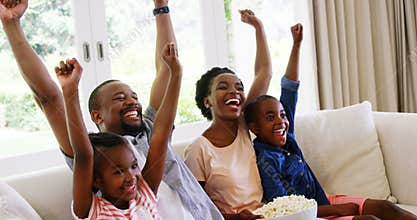 Parents and kids having fun while watching television in living room