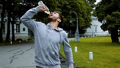 Sportsman drink clean water from bottle splashing water.
