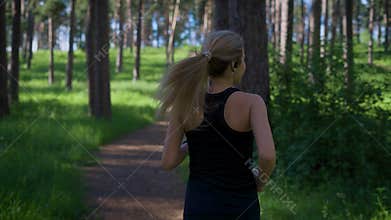 Woman jogging in the park. She switching music on her music player