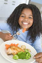 Girl eating chicken and vegetable dinner at home