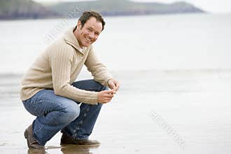 Man crouching on beach