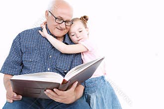 Grandfather reading a book with granddaughter