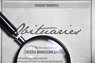 Magnifying glass and obituaries advertisement on newspaper