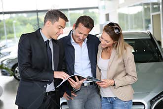 Couple buying new car with car salesman