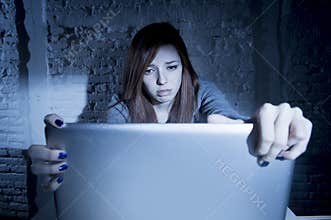 Scared female teenager with computer laptop suffering cyberbullying and harassment being online abused