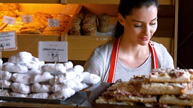 Portrait of female baker holding sweet food in tray