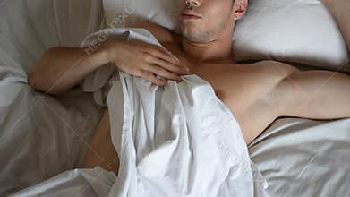 Shirtless male model lying alone on his bed