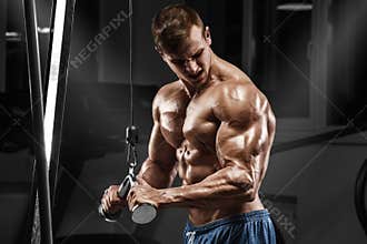 Muscular man working out in gym doing exercises at triceps, strong male naked torso abs