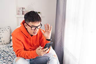 Young Asian happy while using smartphone making facetime video calling, lockdown situation. Social distancing concept