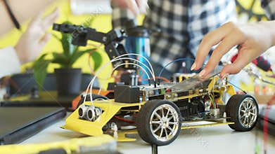 Unrecognizable students assembling car in robotics class