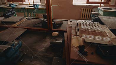 A large abandoned classroom with tables and tools.
