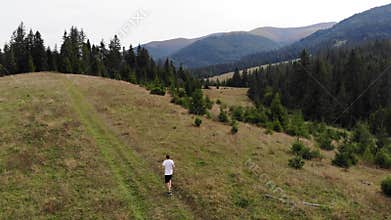 Aerial view of fit man running in mountains forest on weekend, amazing trail running moments, achieving fitness goals