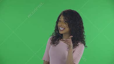 Portrait of beautiful african american young woman is looking at camera winks coquettishly and points fingers at someone