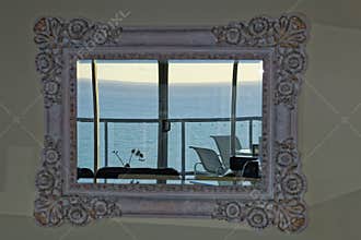 Retro mirror in living room with view to ocean from top floor apartment